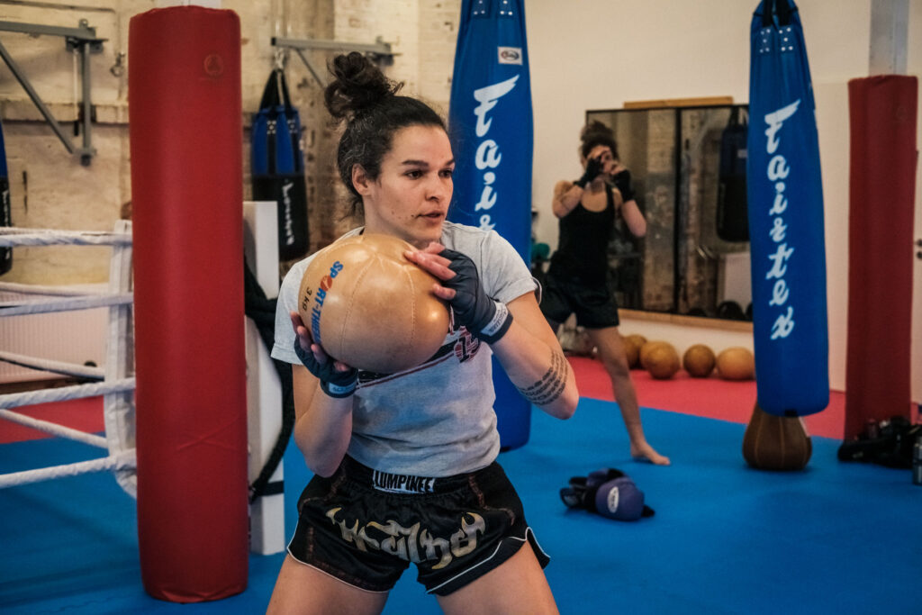 A person throwing a medicine ball. Another person doing shadow boxing.