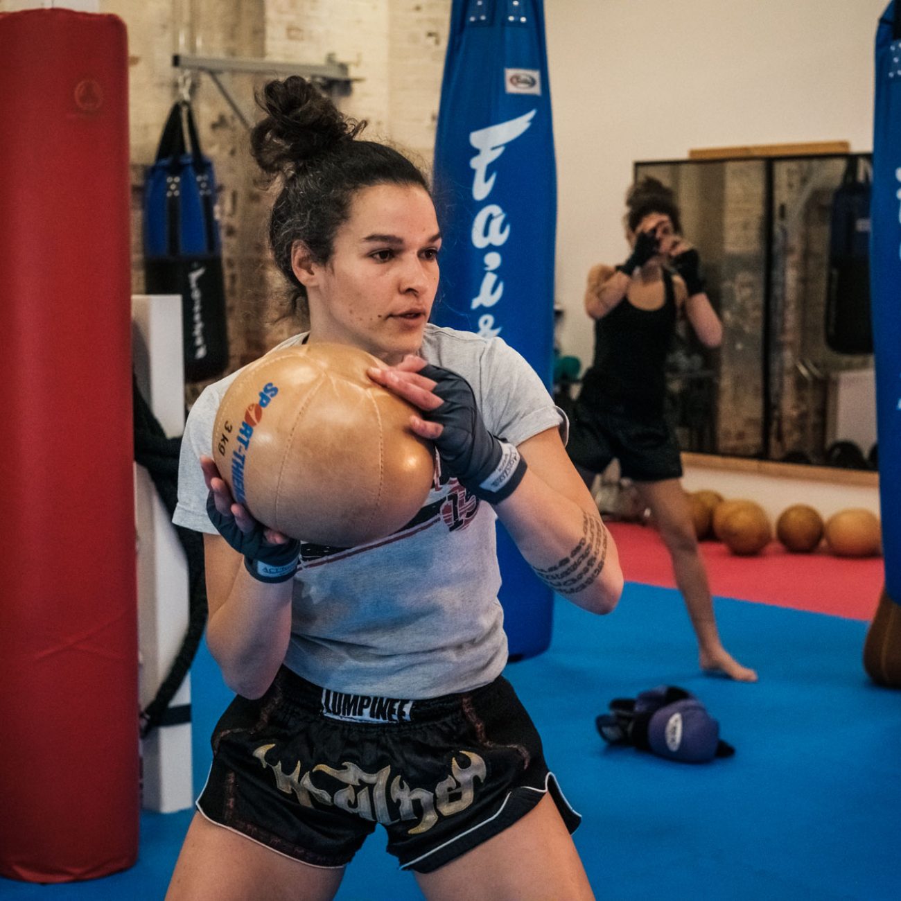 A person throwing a medicine ball. Another person doing shadow boxing.
